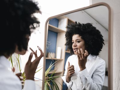woman looking at sebaceous filaments in mirror
